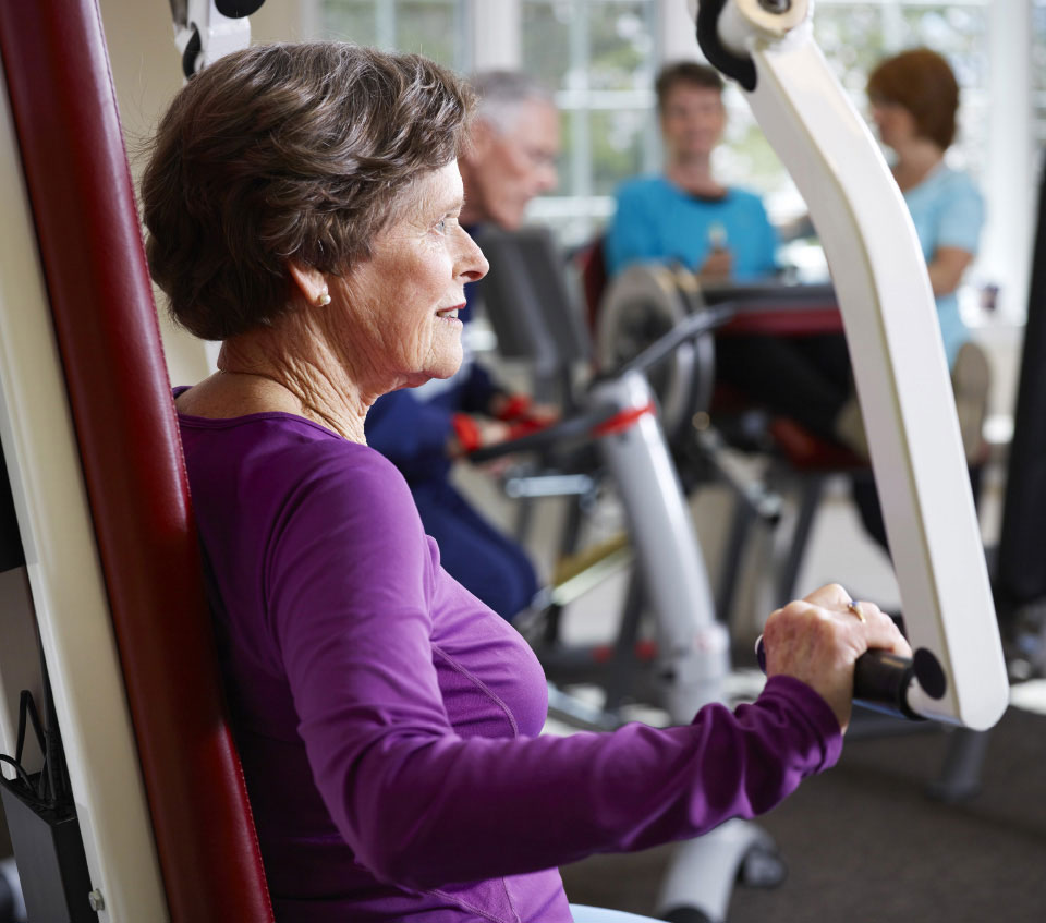 woman in purple shirt on arm weight machine